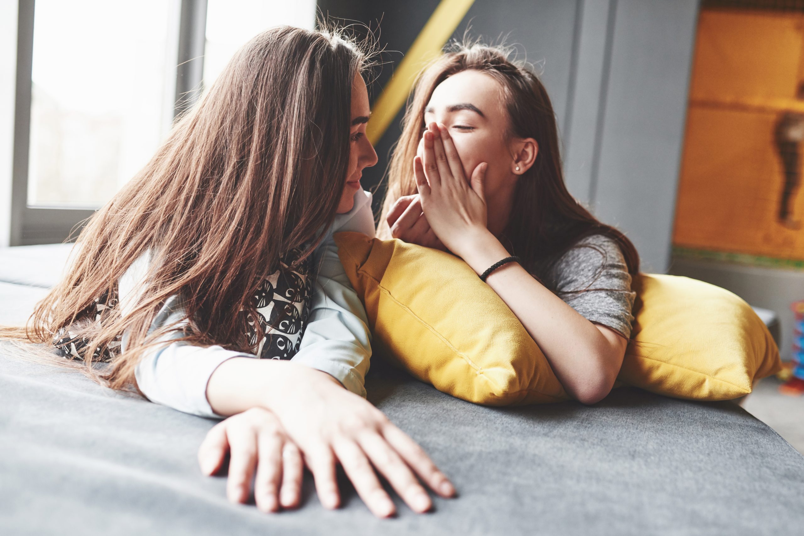 Two beautiful young twins sisters spending time together with pillows. Siblings having fun at home concept
